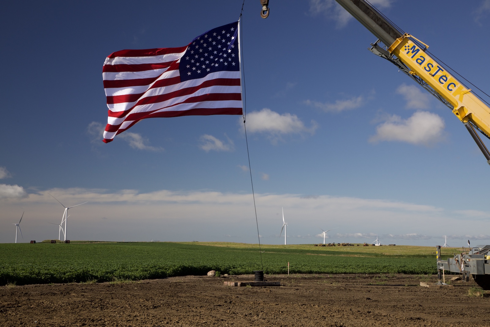 Flag hanging from crane in front of wind farm