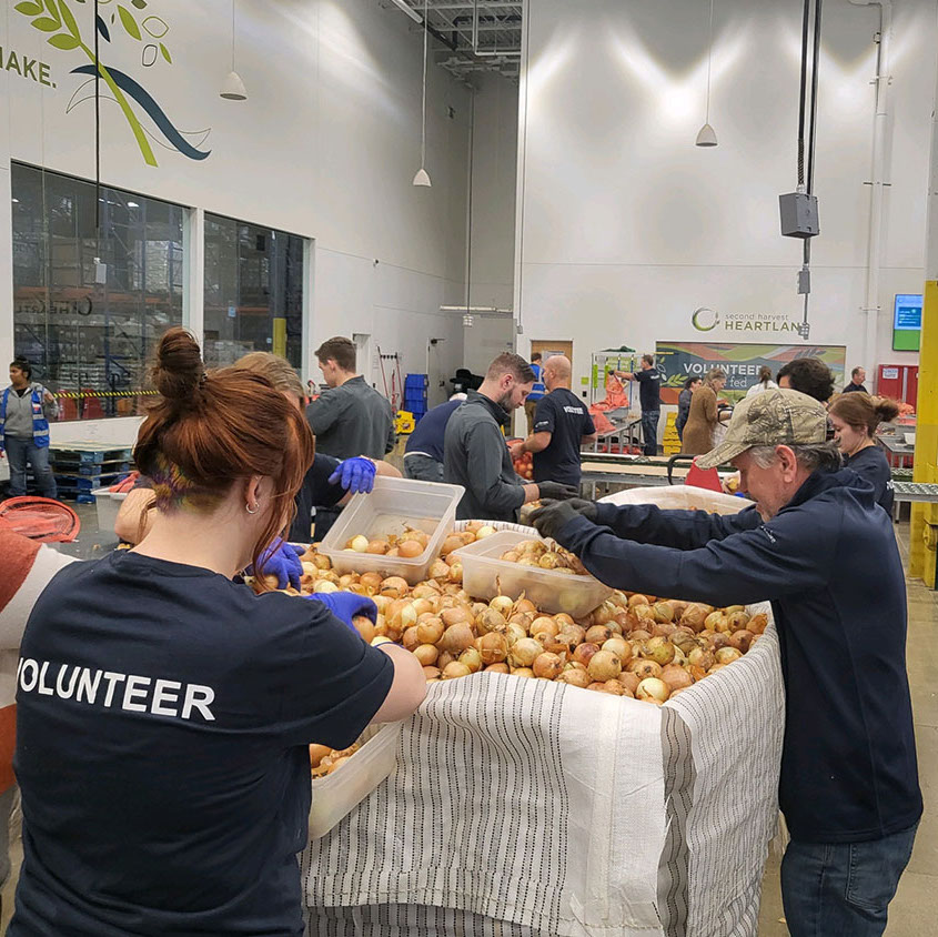 Team volunteering at Second Harvest Heartland with bin of onions