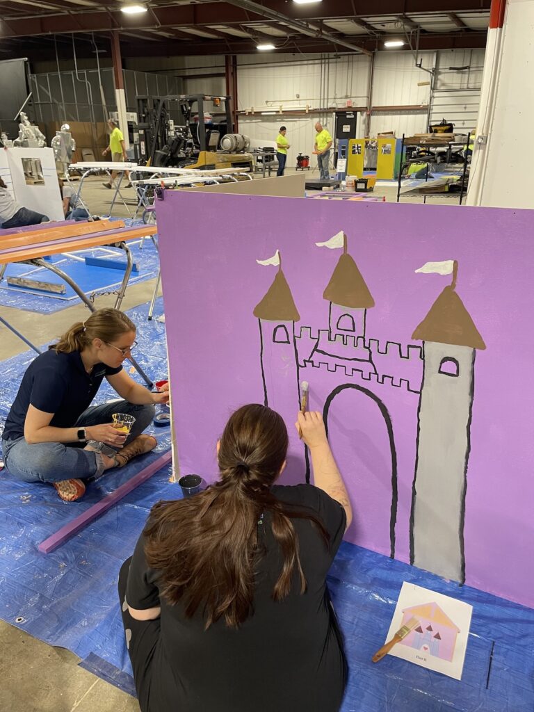 Team members painting a playhouse