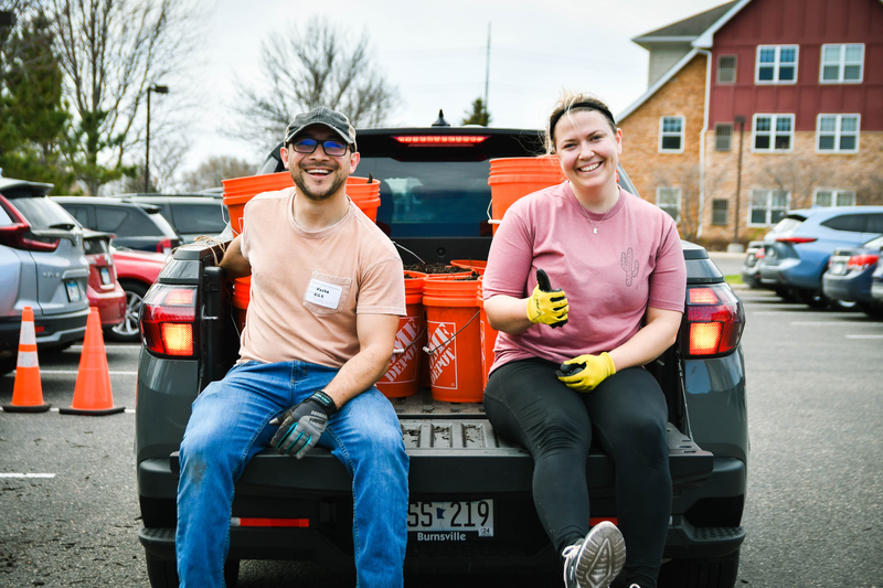People on the back of a pick-up truck with buckets