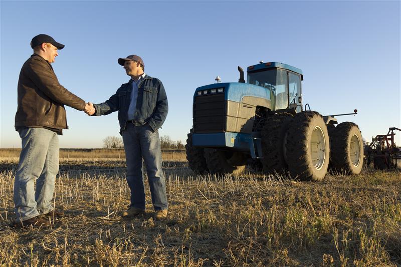 Farmers shaking hands in field