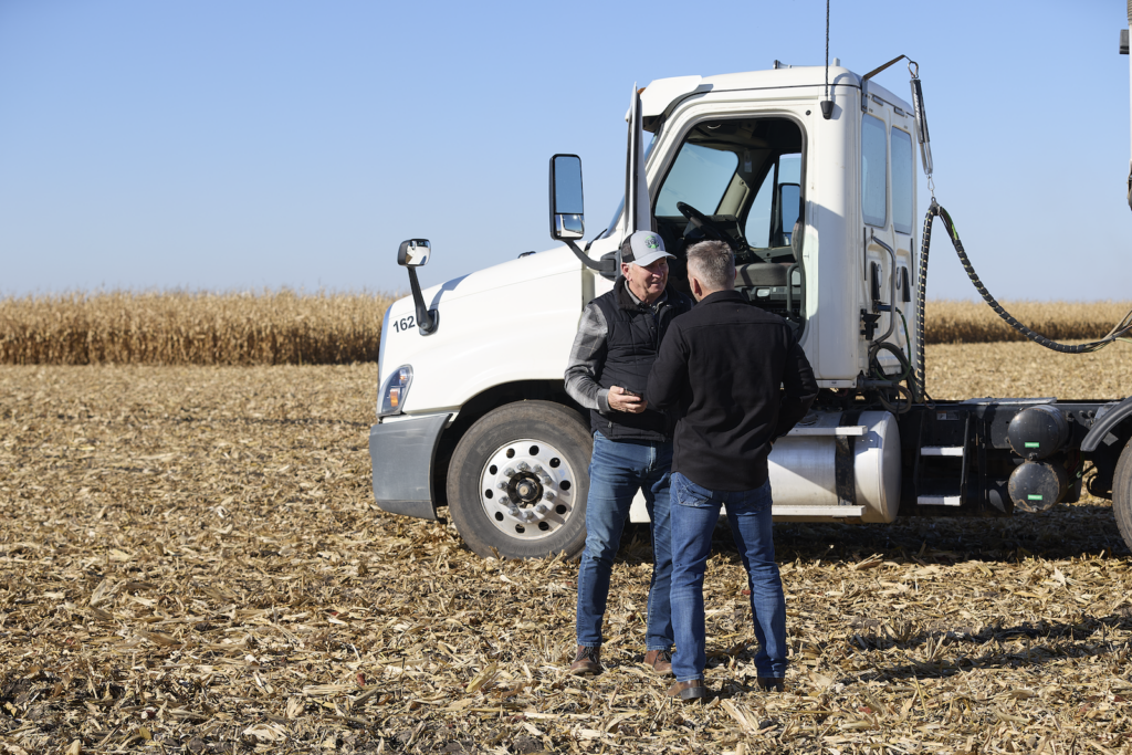 Two men talking in front of truck in field